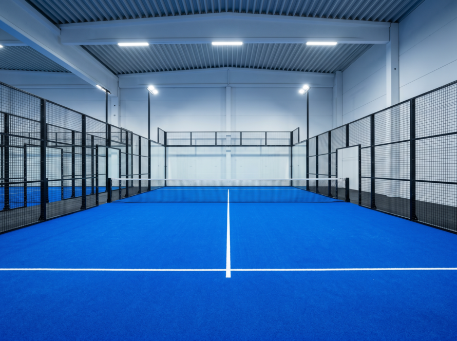 Empty padel court showing the layout, service lines, net and glass walls