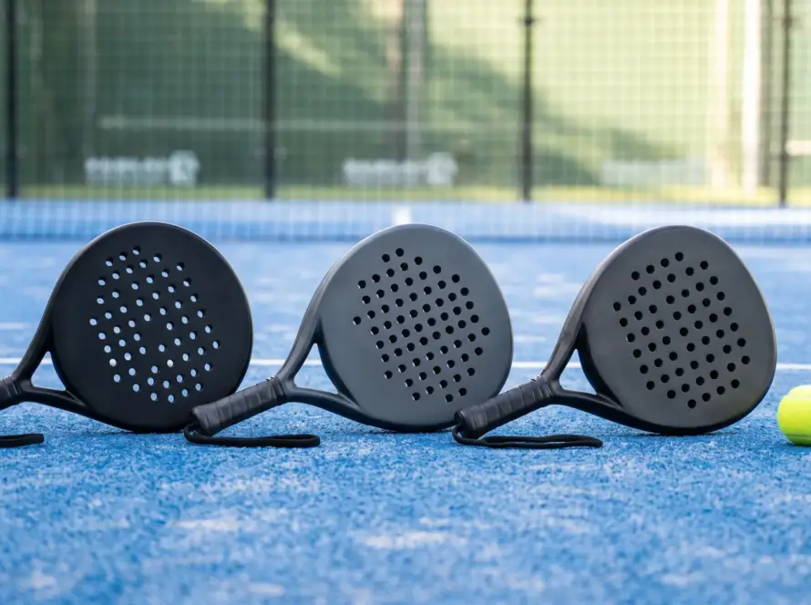Three padel rackets with different shapes laid out on a blue padel court