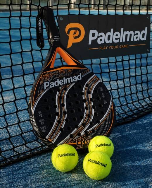 Padelmad branded padel rackets and balls beside the net on a blue padel court